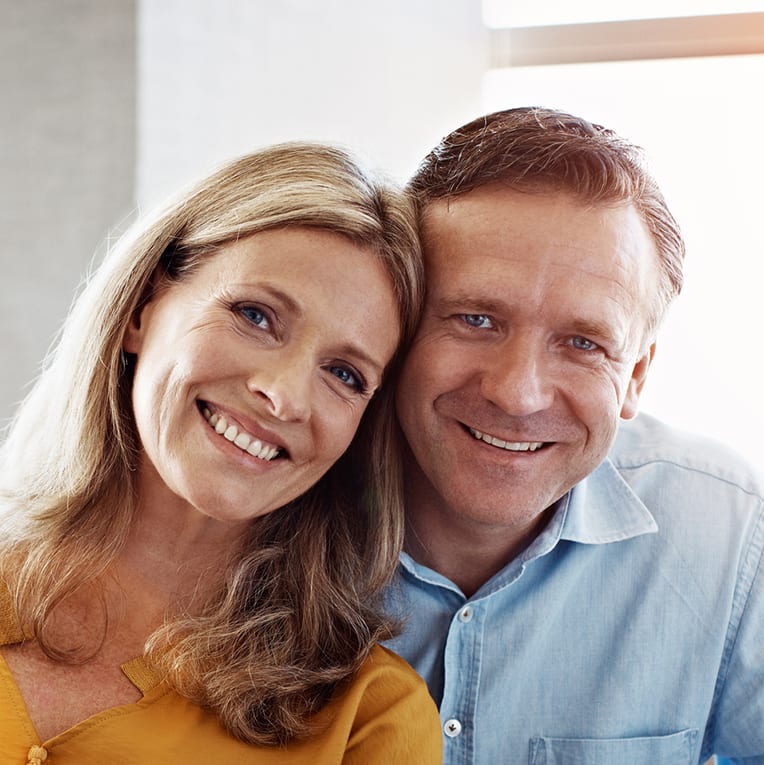 Portrait of a mature couple sitting at their dining room table doing online banking using a digital tablet