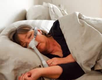 woman sleeping wearing cpap device for sleep apnea
