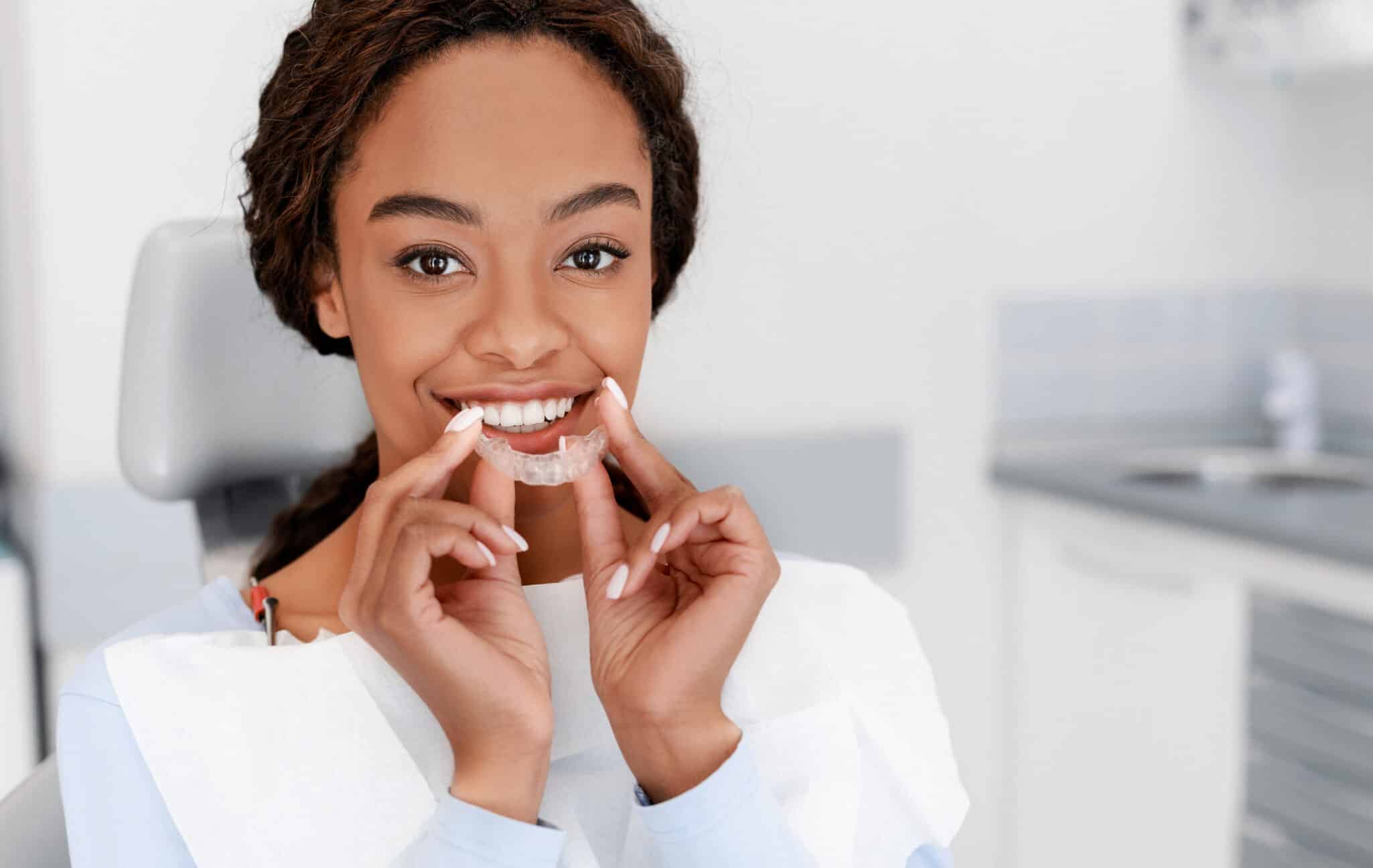 Dental Treatment Concept. Close up of young black woman holding invisalign braces.