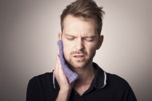 Man in pain holding his cheek with hand suffering from bad tooth ache