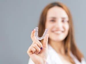 woman is holding an invisalign bracer