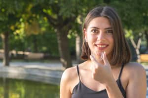 smiling Turkish woman is holding an invisalign bracer