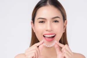 smiling woman holding invisalign braces in studio