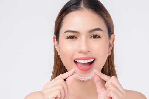 smiling woman holding invisalign braces in studio