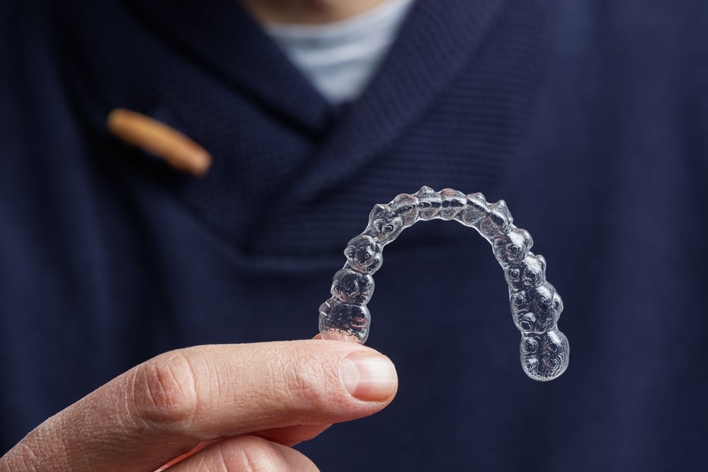 Man,Holding,One,Transparent,Aligner.,Invisalign,Orthodontics,Concept