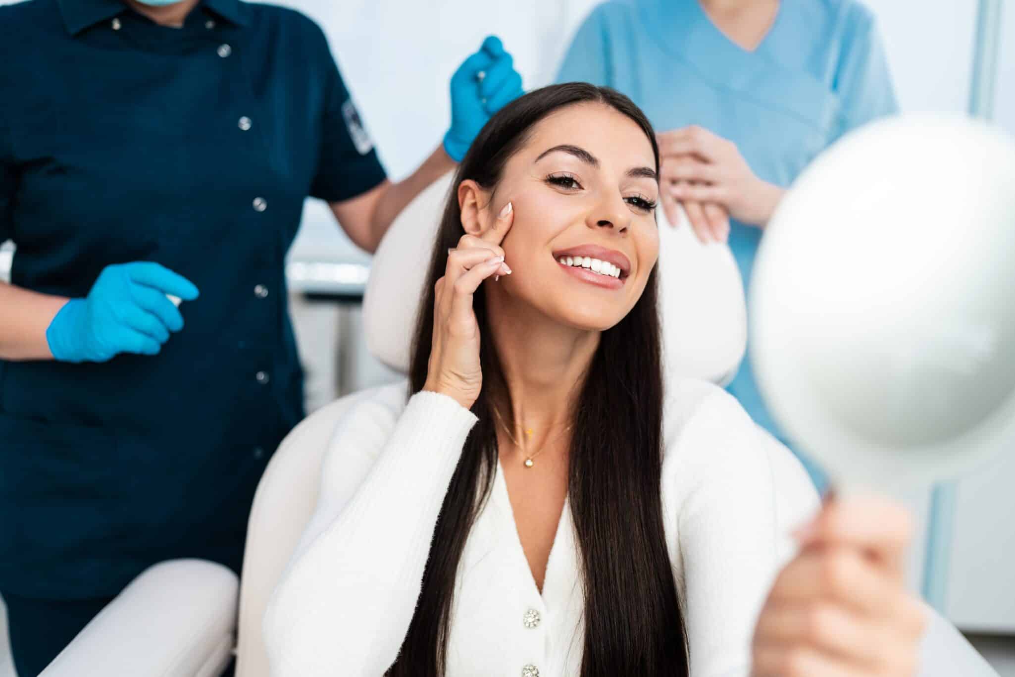 Woman happily checking her smile in the mirror after receiving dental inlays or onlays for tooth restoration