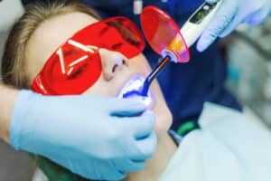 Close up of a female patient benefiting from laser dentistry with her experienced, professional dentist